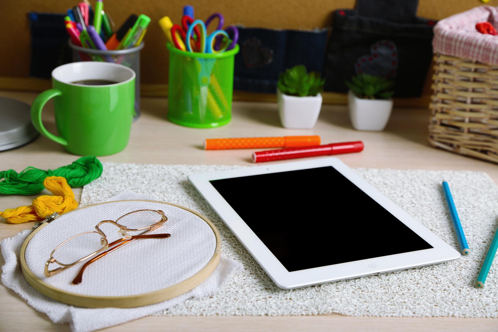 atelier workbench with threads, hoops and a tablet showing vector stitch file